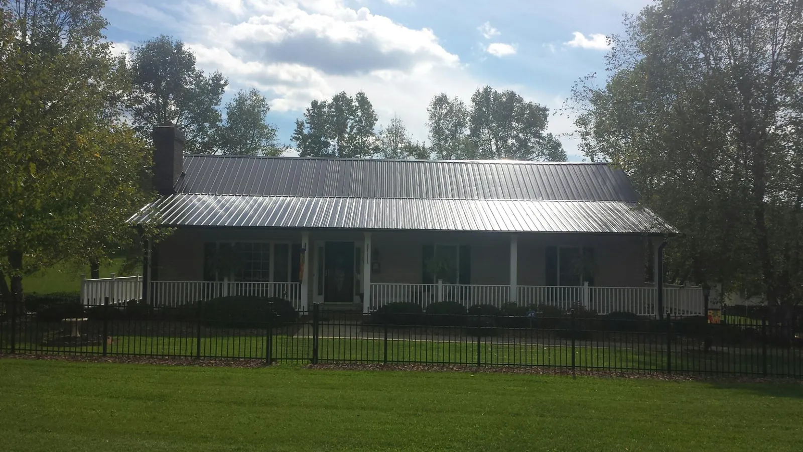 Gray metal roof on a brick ranch with a full width front porch — Gutter Guard Installation work by our crew in Waverly