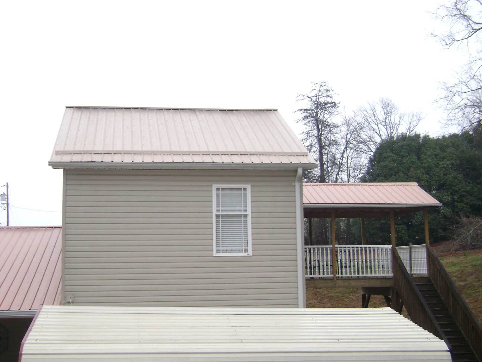 Tan metal roofs on a two story addition and attached porch, from a Roof Replacement job in Waverly